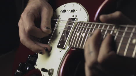 manos con un esmalte de uñas negro en mal estado tocando la guitarra