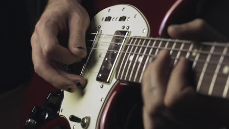 hands with a shabby black nail polish playing the guitar