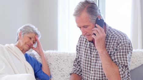 Focused-elderly-couple-calling-doctor