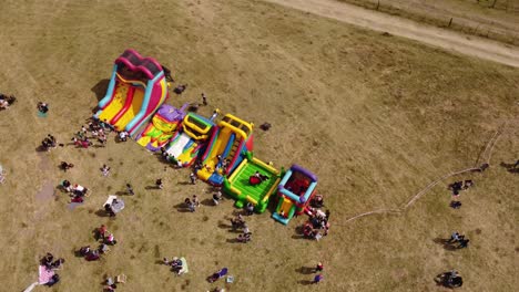 aerial birds eye shot of many children having fun on inflatable bouncer castle in sunlight