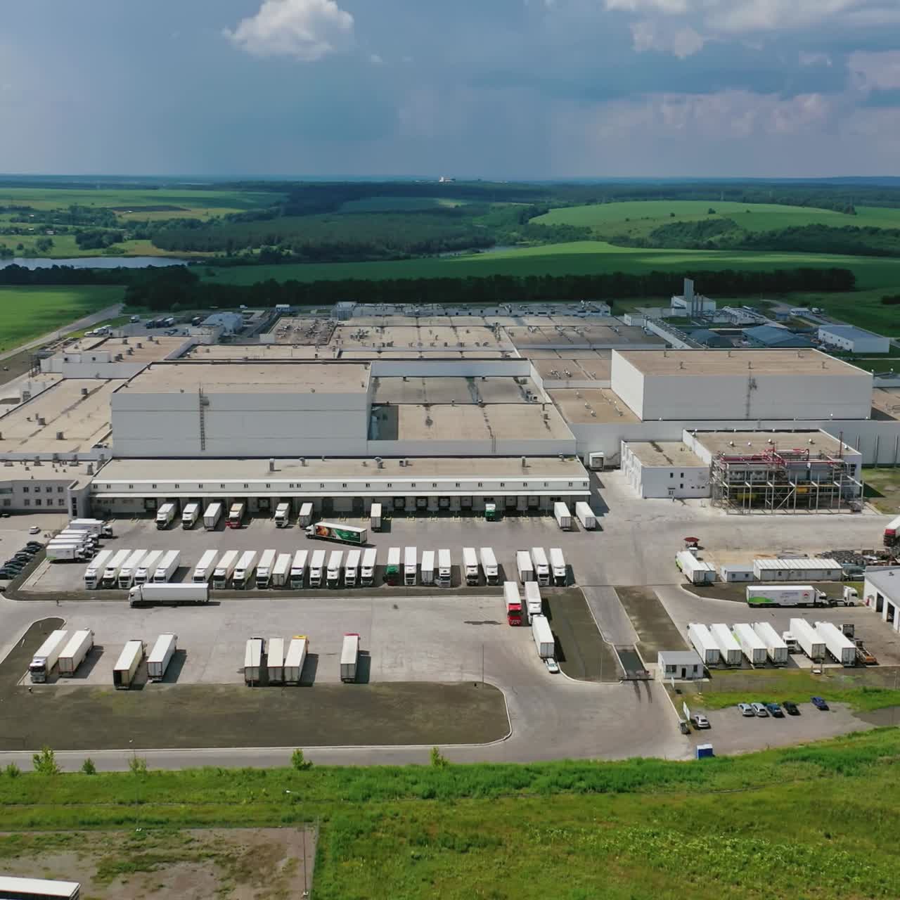 Modern industrial zone among green nature. Large territory of manufacture on the field in the countryside. Aerial view.