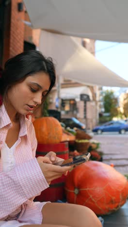 mujer joven usando el teléfono en el mercado al aire libre