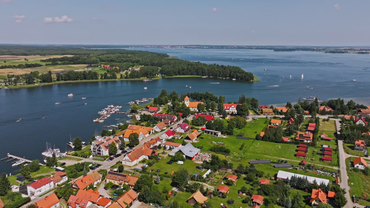 Bright summer aerial view of Rydzewo on Niegocin Lake showing boats and rooftops