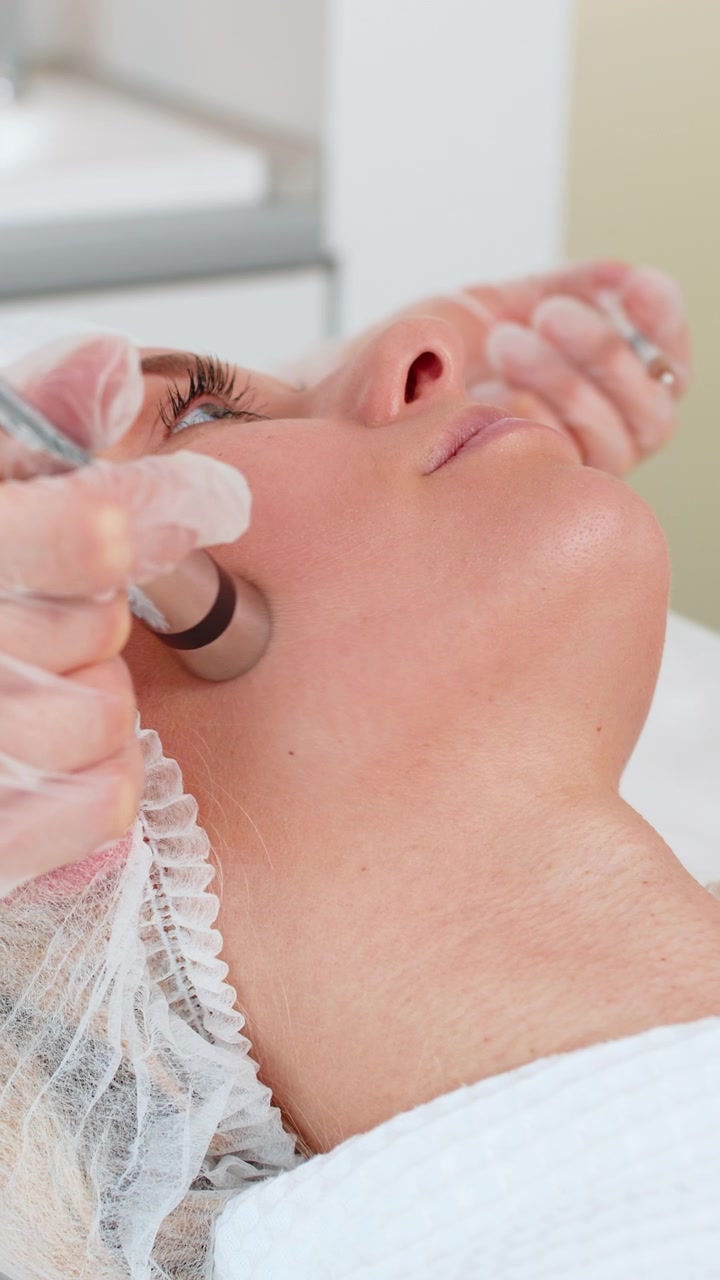 Mesoterapia senza iniezioni o elettroporazione estetista fa la terapia del viso della donna nel salone della clinica