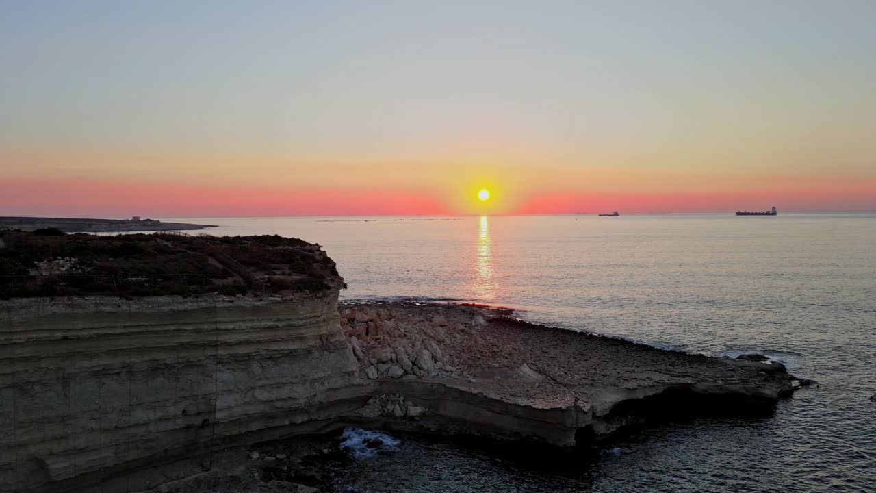 Auringonlasku St. Peterin altaan yllä, jossa näkyy kerroksittain kalkkikivikallioita ja tyyni Välimeri