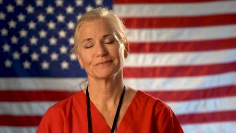 medium tight portrait of nurse looking relieved, happy and nodding her head with american flag behind her