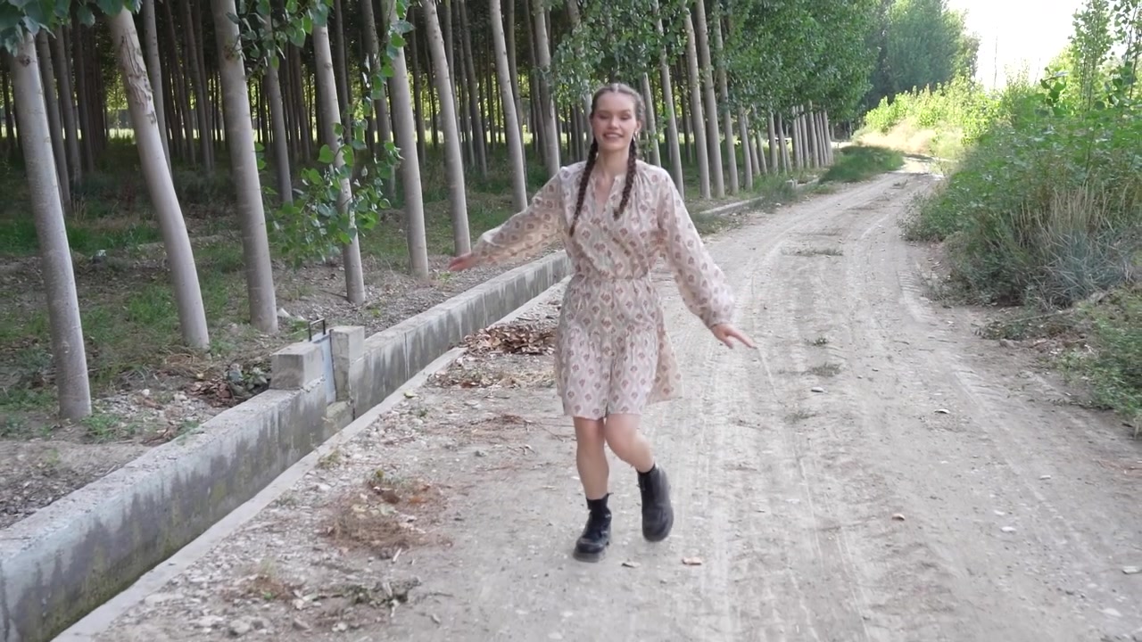 Una giovane donna cammina su un sentiero forestale sereno e incantevole, circondata dalla bellezza della natura.