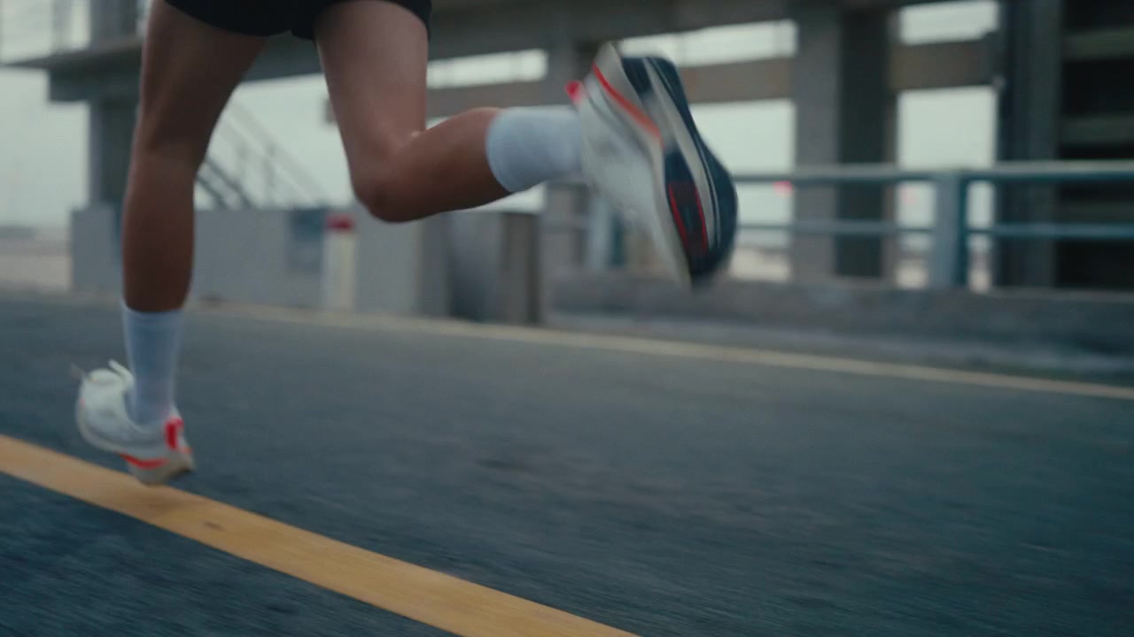 Close tracking follow of runner legs moving on concrete pier during early morning workout session