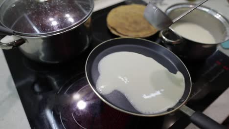 the process of cooking homemade pancakes. woman pours pancake dough on pan