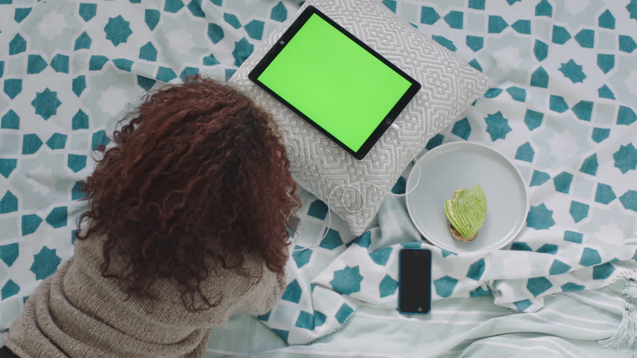 vista in alto giovane donna che usa un tablet pc che guarda lo schermo verde che si rilassa a letto a casa adolescente che studia chroma key