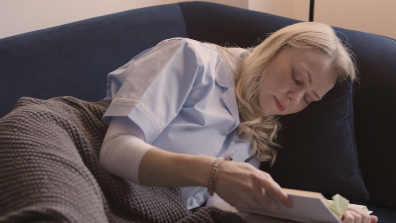 Donna che legge un libro su un divano