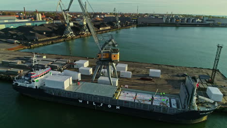 grúa portuaria móvil cargando carga en un buque de transporte en el puerto industrial