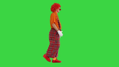 funny clown with red hair walking comically on a green screen, chroma key