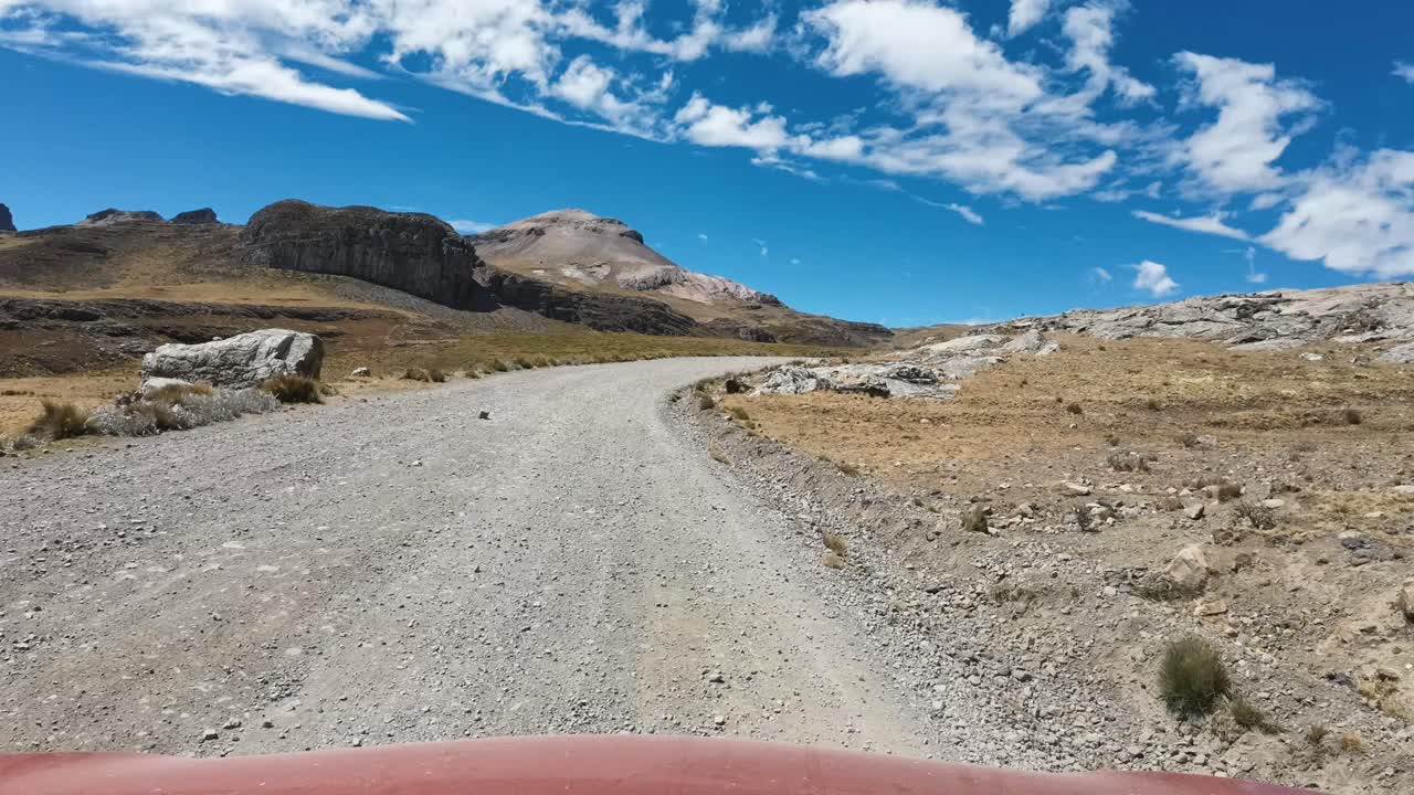 POV Conduciendo por una carretera de grava a través de un paisaje montañoso remoto