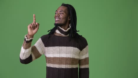 young handsome african man with dreadlocks against green background