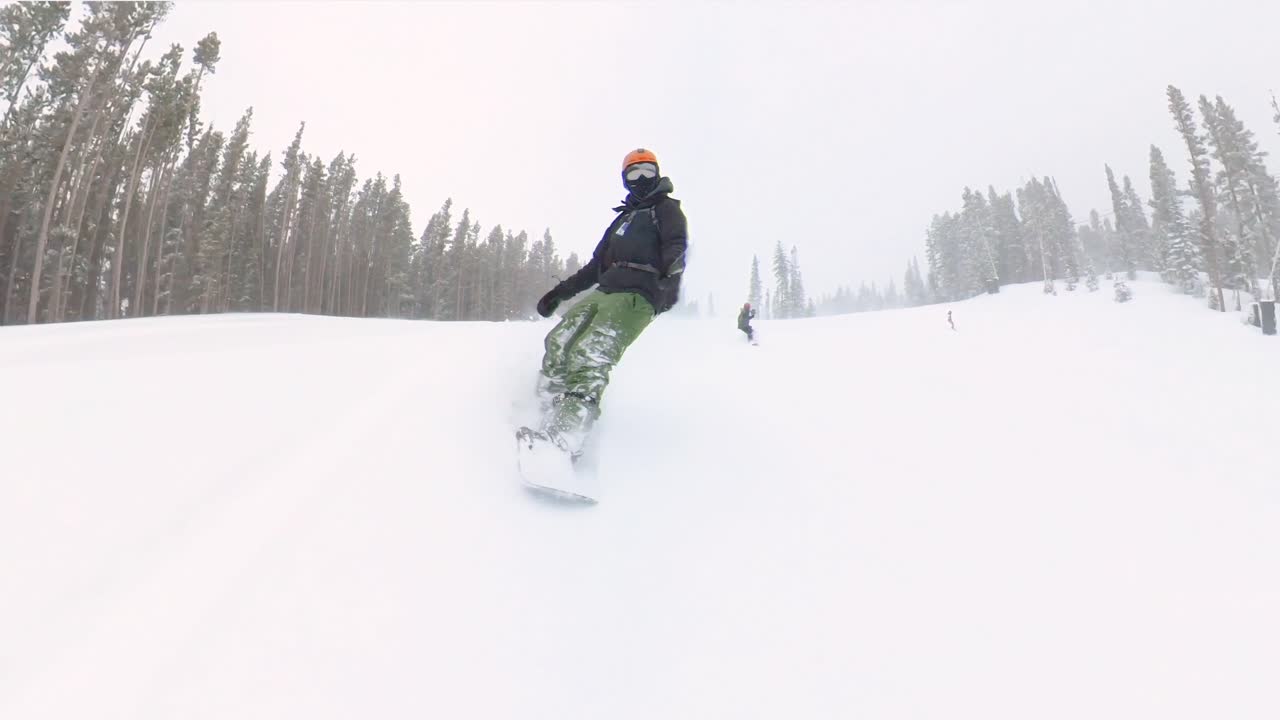 snowboarder masculino tallando a través de nieve en polvo fresca durante una tormenta de nieve