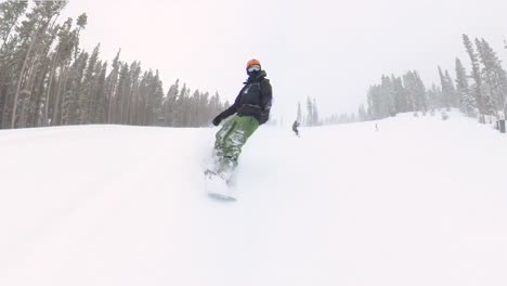 male snowboarder carving through fresh powder snow during a snowstorm