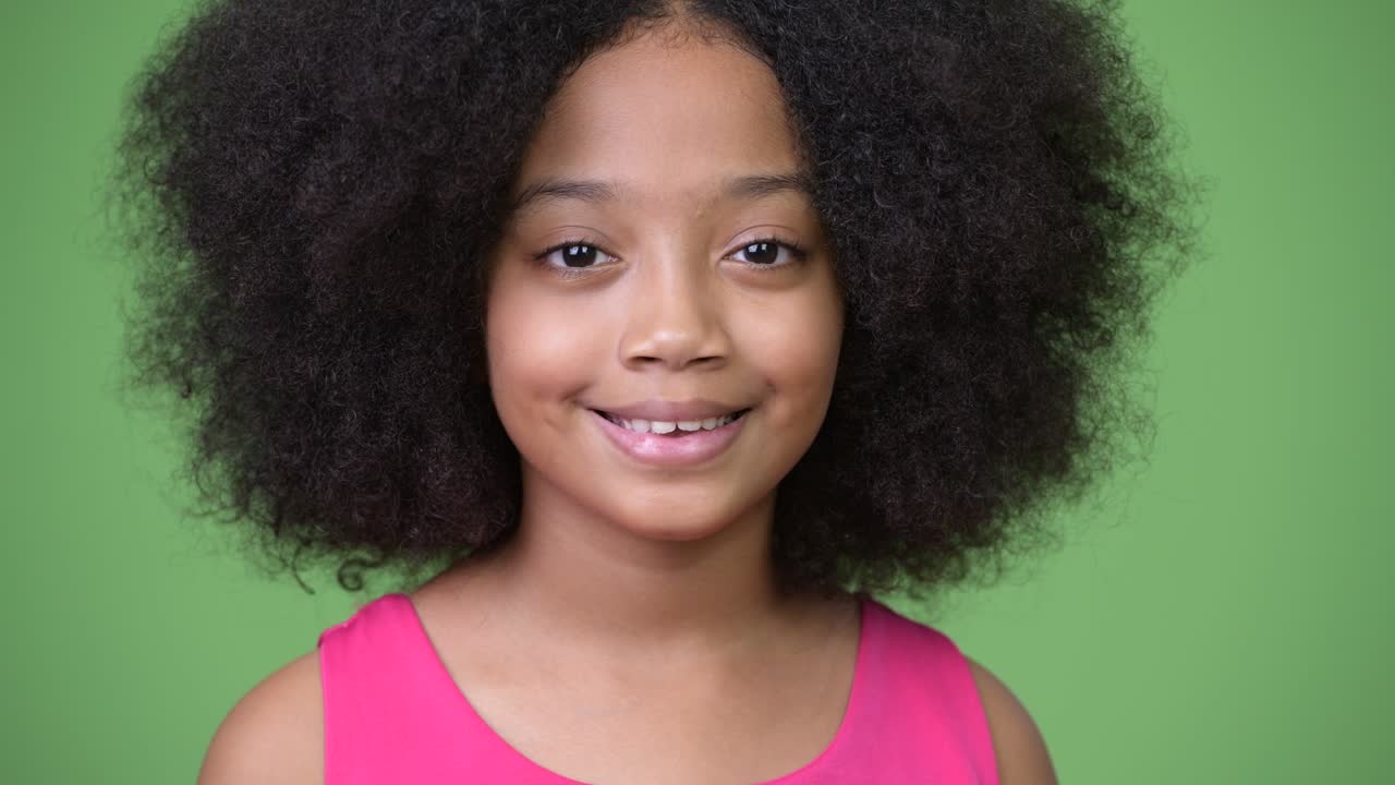 joven chica africana con cabello afro sonriendo contra un fondo verde