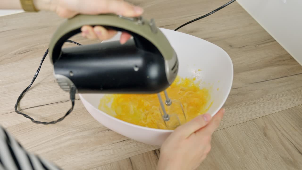 Close-up of egg yolks being mixed with powdered sugar for creamy tiramisu filling.
