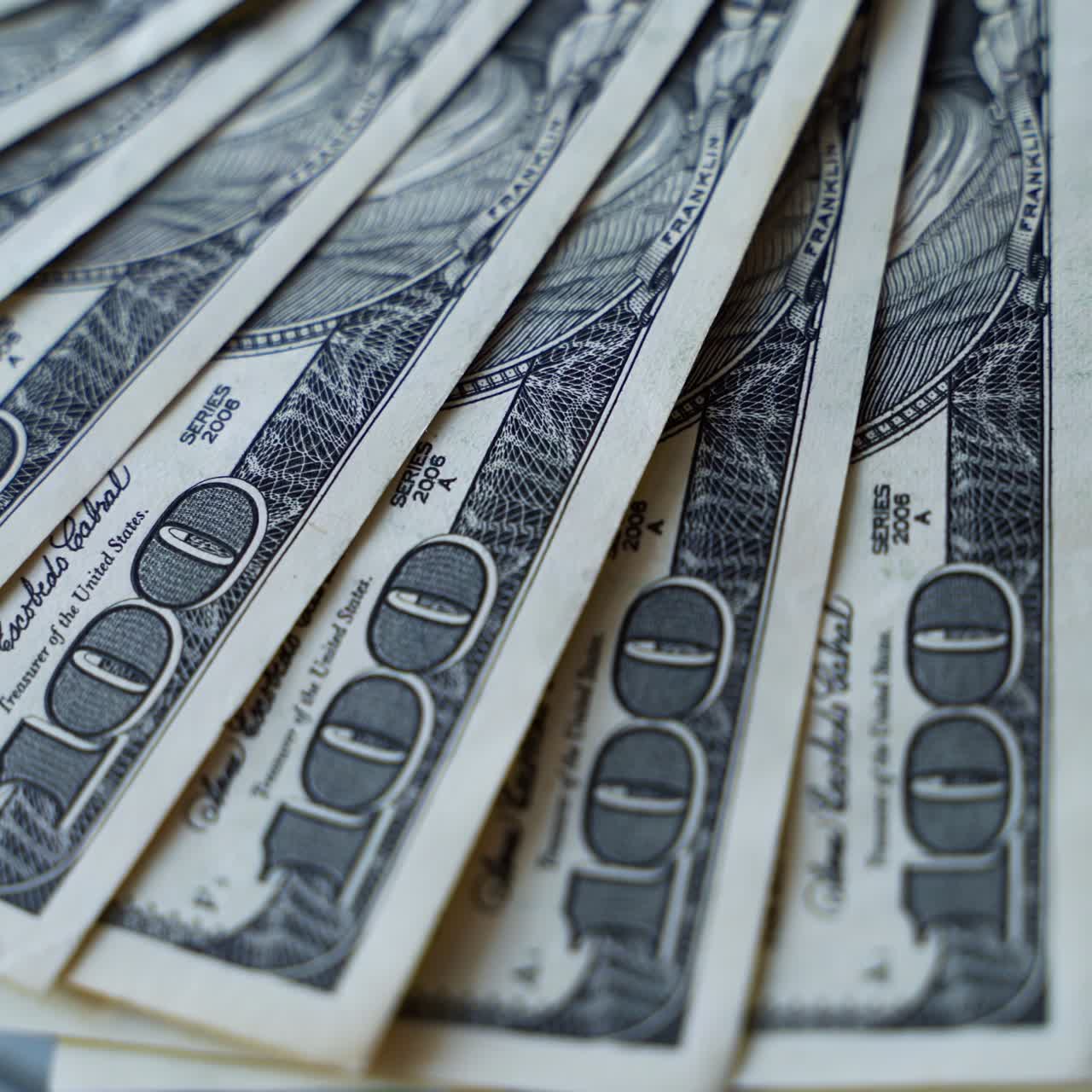 Hundred dollar bills are spinning on a table. Background of american money with one hundred banknotes. Rotation of paper money. Close-up.
