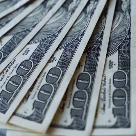 hundred dollar bills are spinning on a table. background of american money with one hundred banknotes. rotation of paper money. close-up.