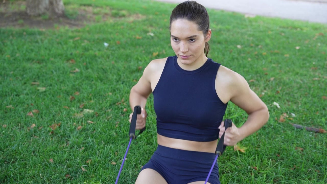 Una mujer haciendo ejercicio en el parque con bandas de resistencia para un estilo de vida activo y saludable.