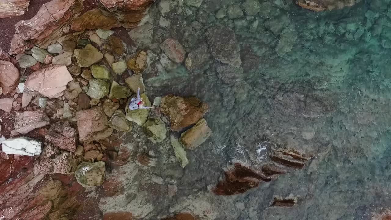 Person står på klipper ved kysten