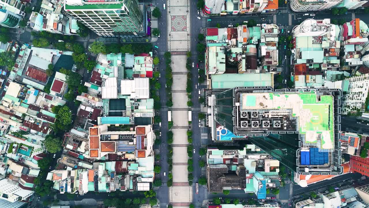 A top-down aerial view of Nguyen Hue Boulevard in Ho Chi Minh City reveals a symmetrical cityscape with modern buildings, narrow streets, and vibrant urban geometry. Vietnam