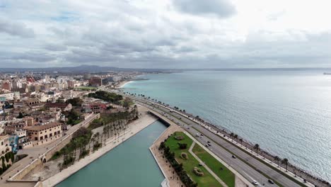 aerial flight over coastal road of palma de mallorca with traffic and bay during cloudy day, spain