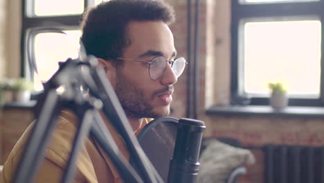 close up view of man with eyeglasses talking into a microphone recording a podcast