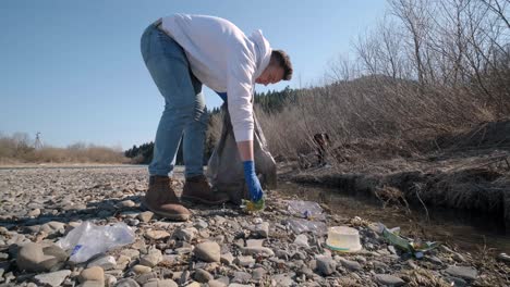 teamwork cleaning plastic on the beach. volunteers collect trash in a trash bag. plastic pollution and environmental problem concept. voluntary cleaning of nature from plastic. greening the planet