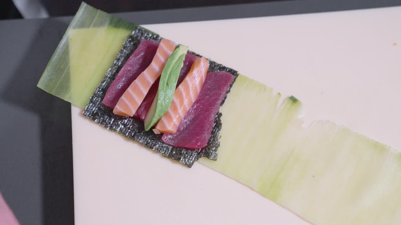 A static overhead shot of a sushi roll being prepared, showcasing the sushi-making process. Perfect for highlighting Japanese cuisine, sushi preparation, and culinary skills in action.