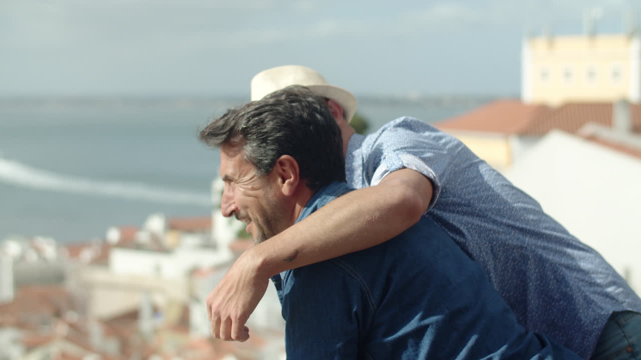 Gay hugging his boyfriend who looking at city from vantage point