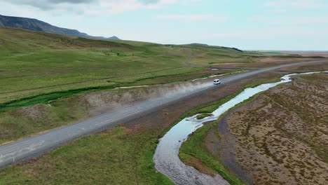 jeep 4x4 conduciendo a través de la pista de tierra polvorienta a lo largo del arroyo en el sur de islandia