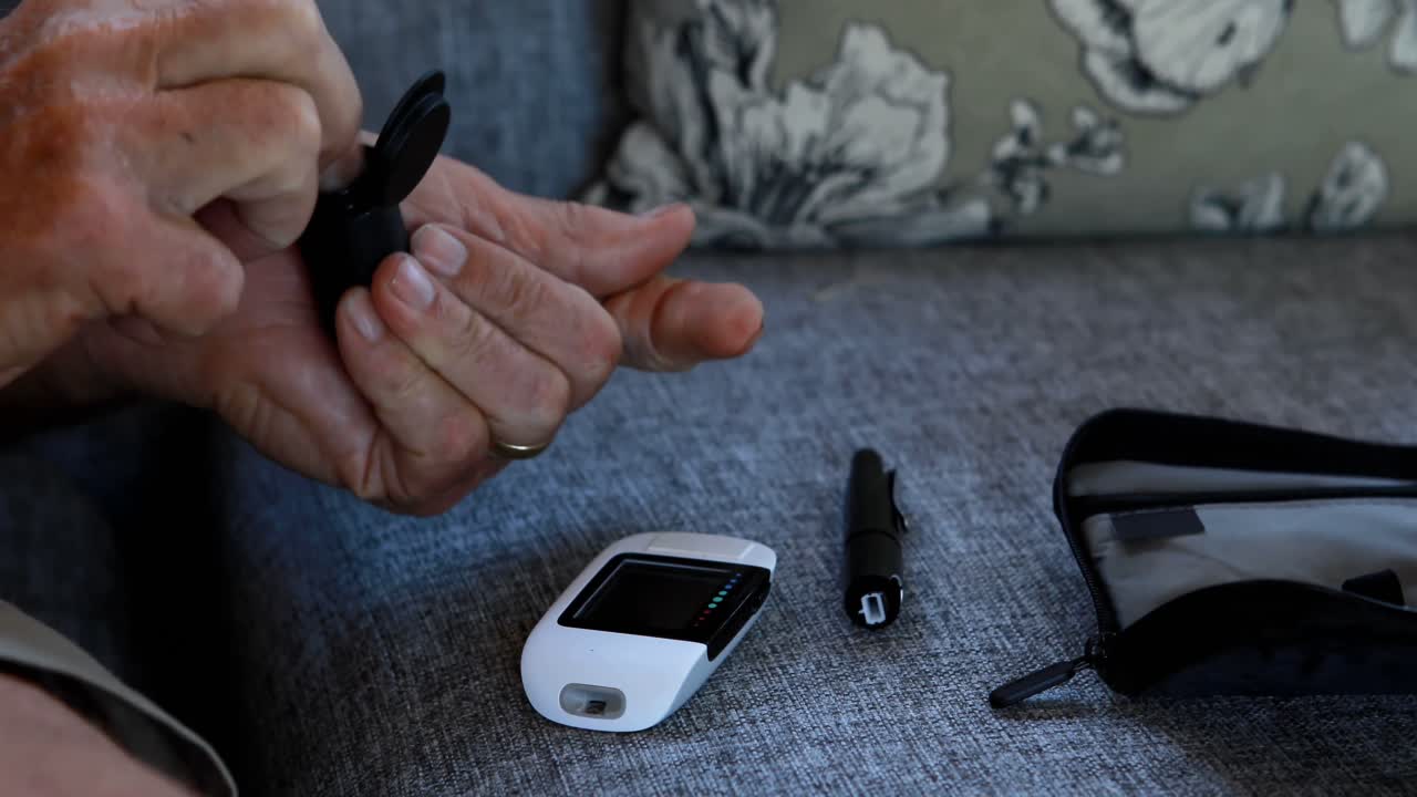 시니어 남자가 혈당 측정기 4k에서 혈당을 확인하고 있습니다.