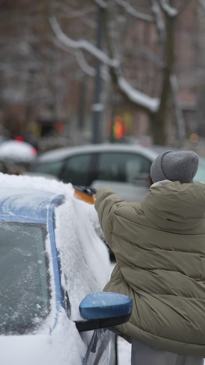 mujer quitando la nieve de un coche en invierno