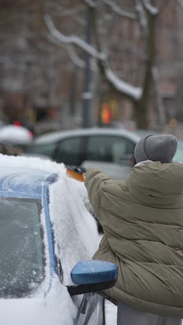 woman removing snow from a car in winter