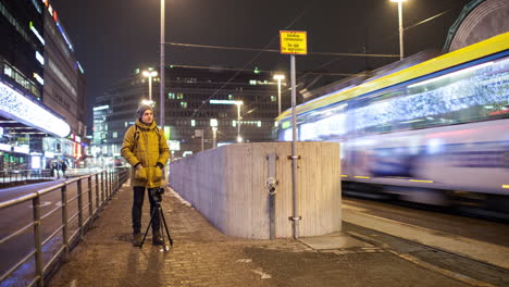 Timelapse-De-Un-Hombre-Grabando-Vídeo-En-Helsinki-Nocturno-Con-Tráfico-De-Transporte