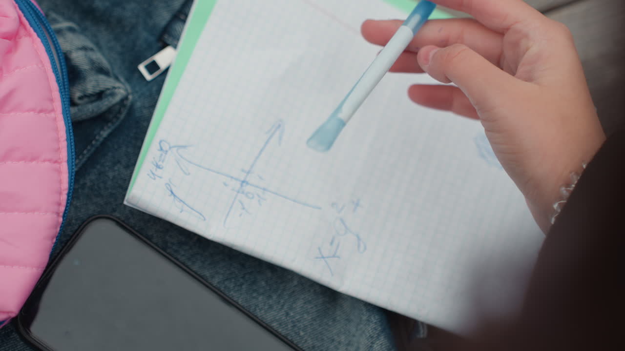 Studente che disegna un grafico su carta millimetrata con una penna blu, tracciando assi e coordinate accanto a un telefono e uno zaino rosa. Le inquadrature della scena di studio all'aperto cambiano tra esercizi di matematica, preparazione per le ripetizioni e veloce