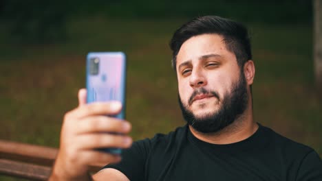 Close-up-young-man-smiling-communicates-outdoors-via-video-call-on-a-mobile-phone