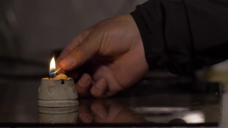 candle lit by a man's hand with out-of-focus background, power outage concept