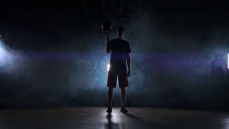 basketball player performing different tricks and spinning ball in dark gym with smoke. slow motion