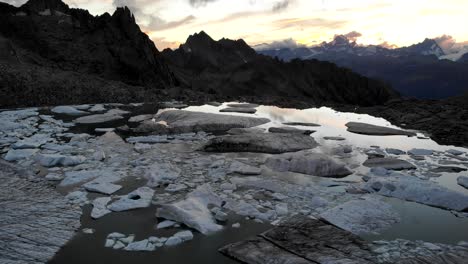 Luftaufnahme-Eines-Sees-Voller-Eisberge-Von-Einem-Schmelzenden-Gletscher-In-Abgelegenen-Teilen-Der-Schweizer-Alpen-Während-Des-Sonnenuntergangs