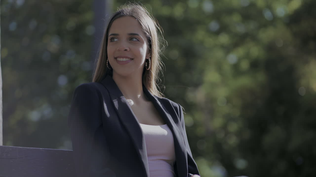 chica sonriente atractiva sentada en un banco al aire libre