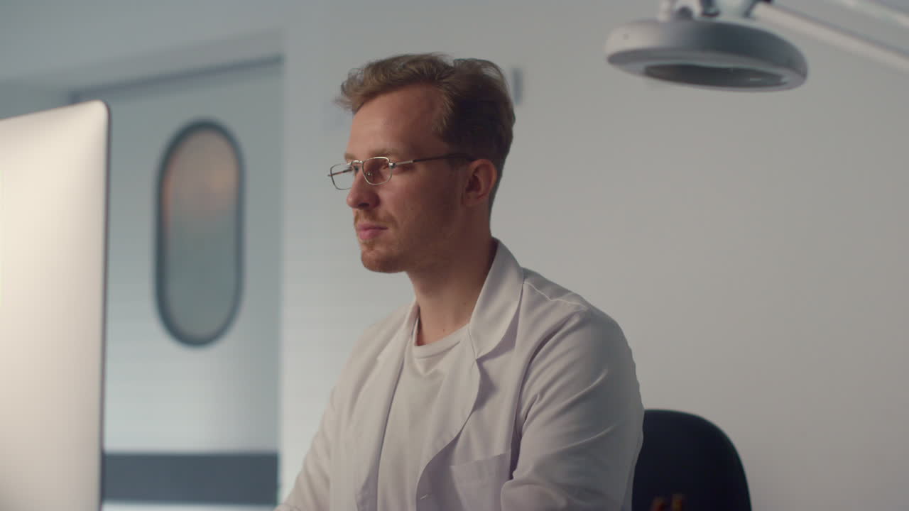 Portrait doctor working computer in modern clinic. Therapist watching monitor.