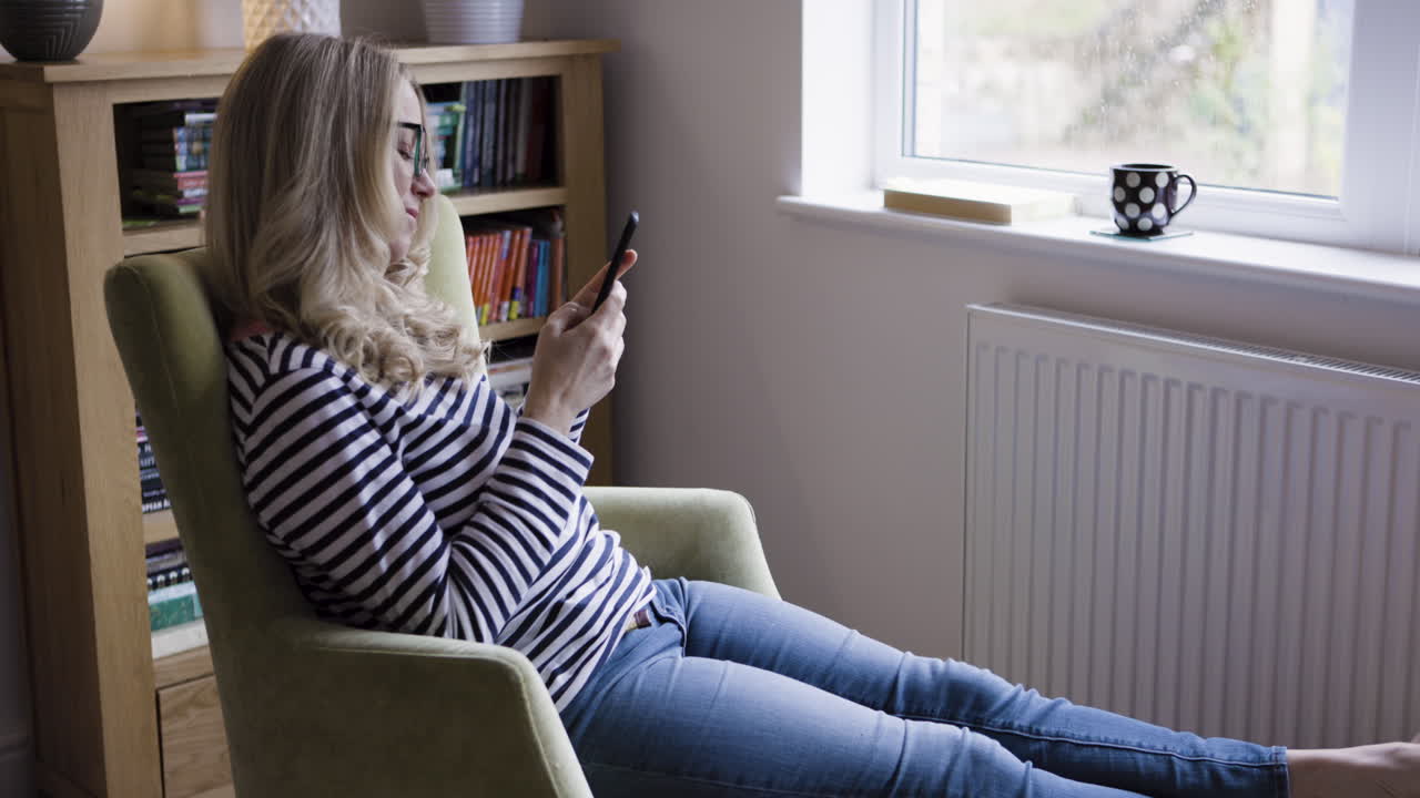 Woman reading a cell phone in a chair