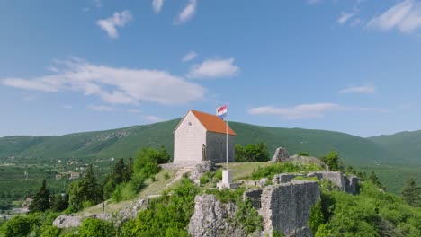 Aerial-parallax-of-Our-Lady-of-Sinj-Church-on-green-hill-in-Croatia