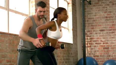 trainer helping client lift weights