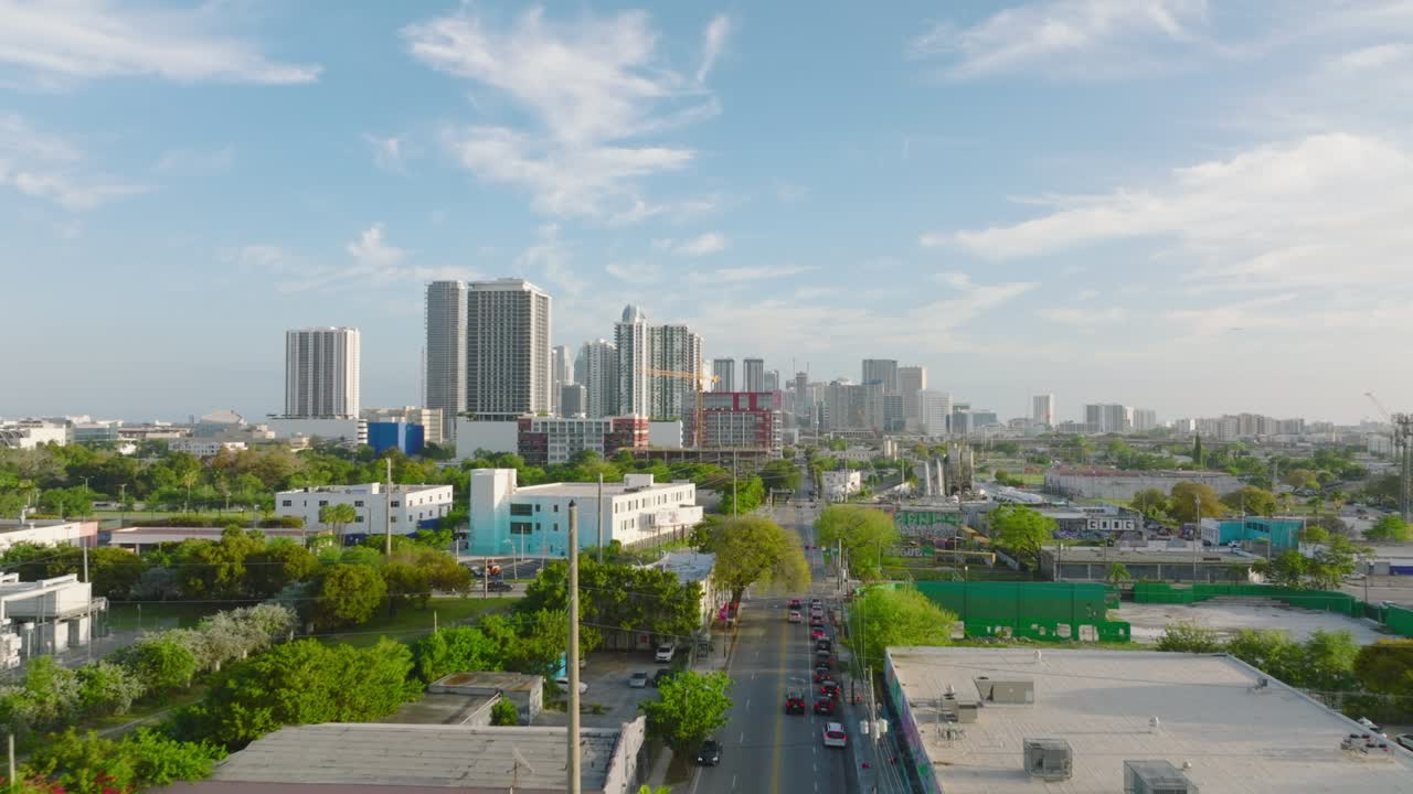 도시 의 거리 위 에 날아다니는 포워드 들. 철도 선로 를 따라 있는 낮은 건물 들 과 나무 들. 배경 에 있는 현대적 인 고층 주택 들. 마이애미, 미국