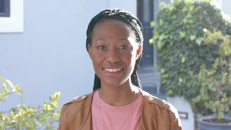 portrait of happy african american woman smiling in sunny garden, copy space, slow motion